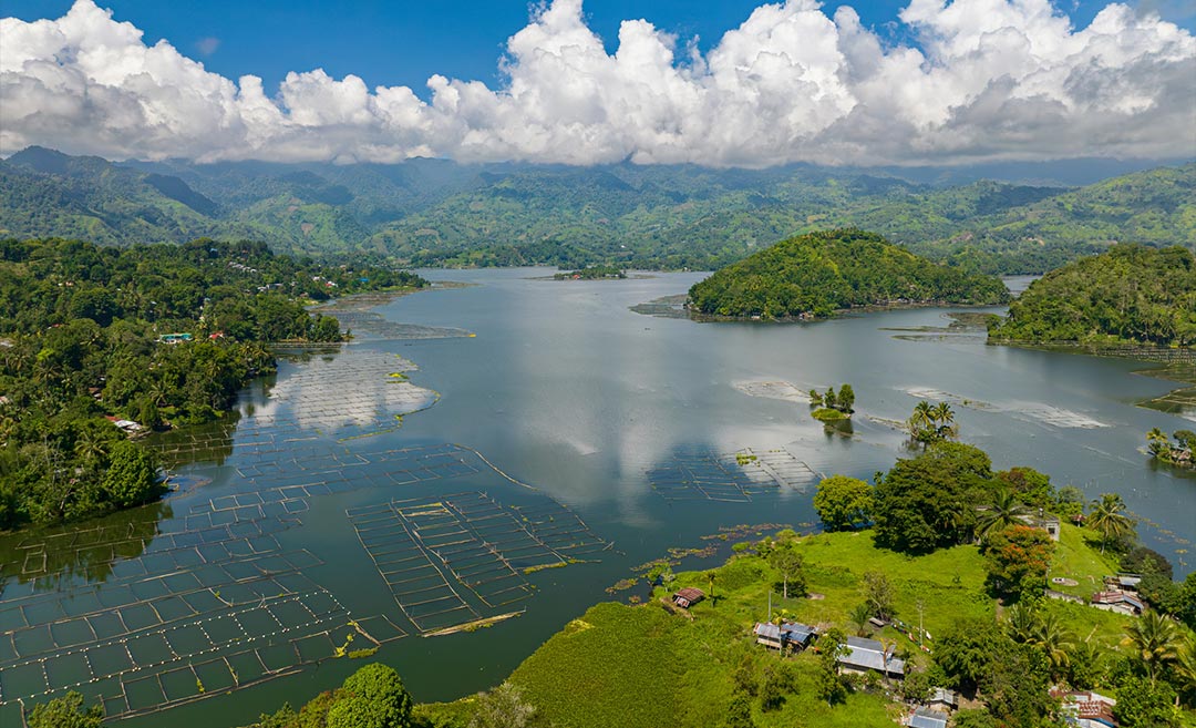 Daytime view of Lake Sebu in South Cotabato, Philippines, featuring peaceful waters framed by lush mountain rainforests in Mindanao.