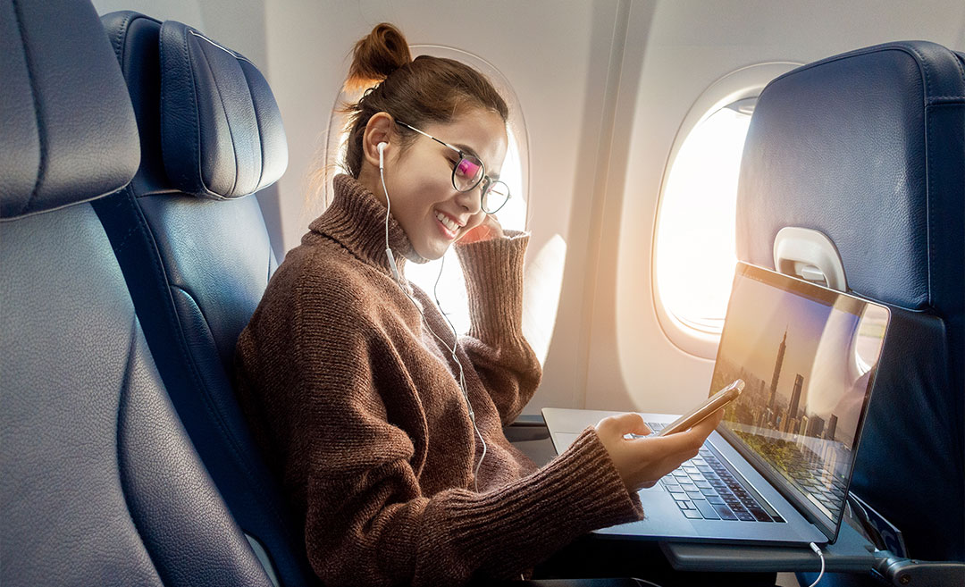 Professional woman working on a laptop computer while seated in an aeroplane during a business flight.