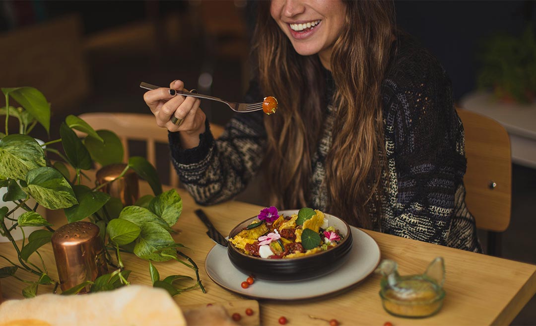A woman enjoying a meal alone at a restaurant table, representing independent travel and confidence.