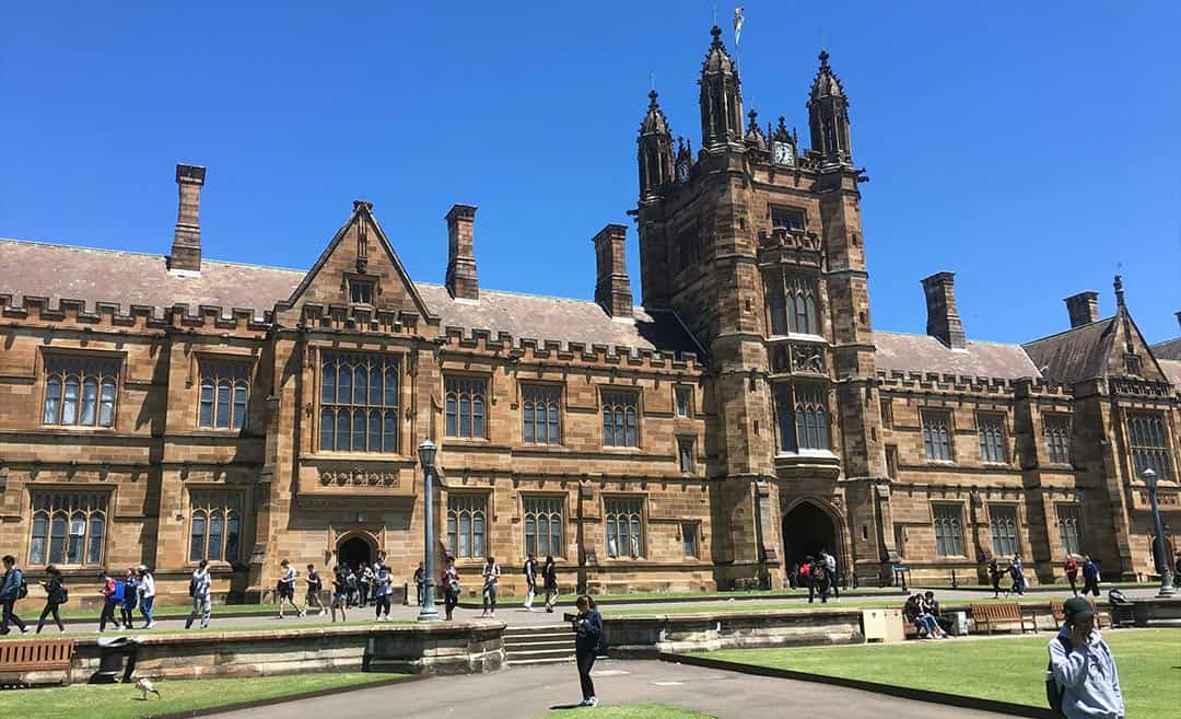Students walking past the historic sandstone Quadrangle Clocktower at the University of Sydney in Camperdown, New South Wales.