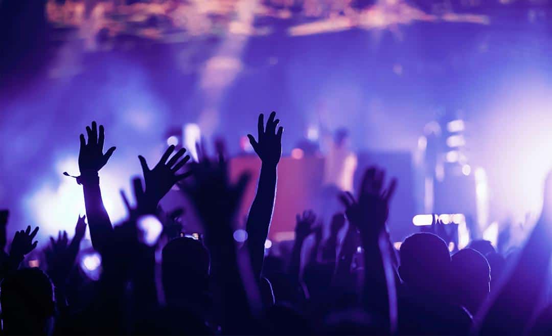 Music fans and travellers with hands raised in the air enjoying a live concert at an indie venue in South Korea.